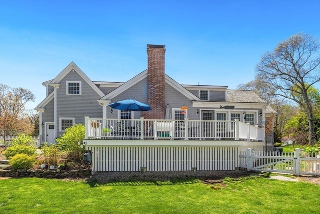 back of house featuring a chimney, a yard, a wooden deck, and fence