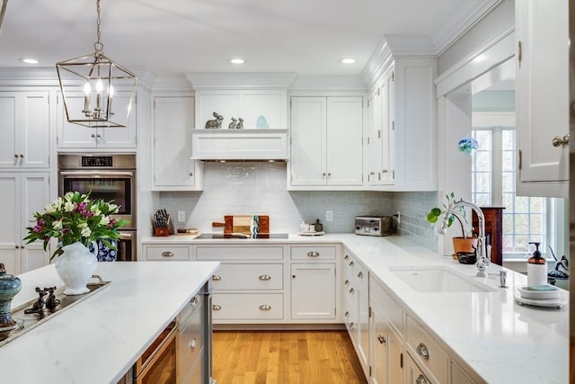 kitchen featuring white cabinets, an inviting chandelier, stainless steel double oven, and a sink