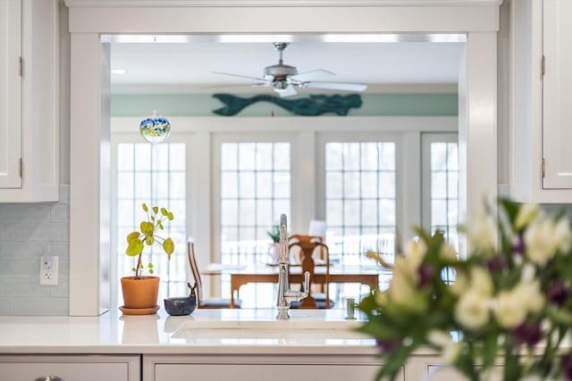 kitchen with a healthy amount of sunlight, ceiling fan, decorative backsplash, light countertops, and white cabinets