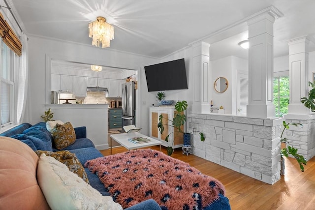 2313 Washington St, Holliston, MA 01746 - living room with ornate columns, light wood-type flooring, a chandelier, and crown molding