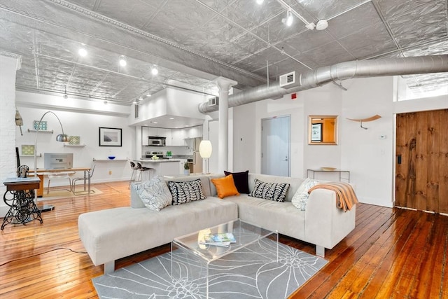 living area with visible vents, a high ceiling, and hardwood / wood-style flooring