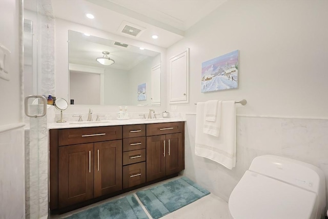 bathroom with vanity, toilet, and tile walls