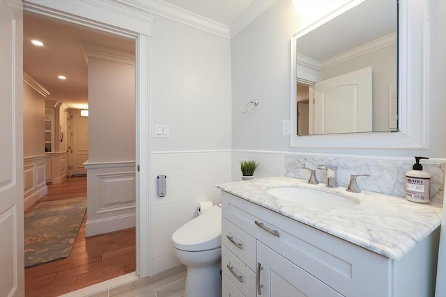 bathroom featuring wood-type flooring, vanity, toilet, and ornamental molding