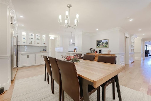 dining area featuring crown molding, light hardwood / wood-style flooring, and a chandelier