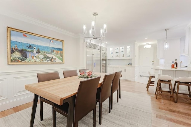 dining space featuring light wood-type flooring, an inviting chandelier, crown molding, and sink