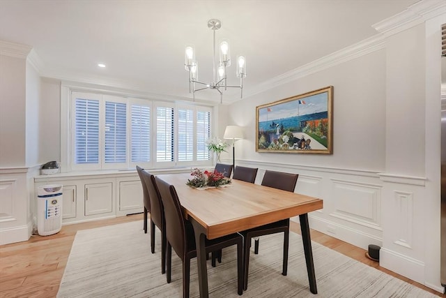 dining space featuring light wood-type flooring, an inviting chandelier, and crown molding