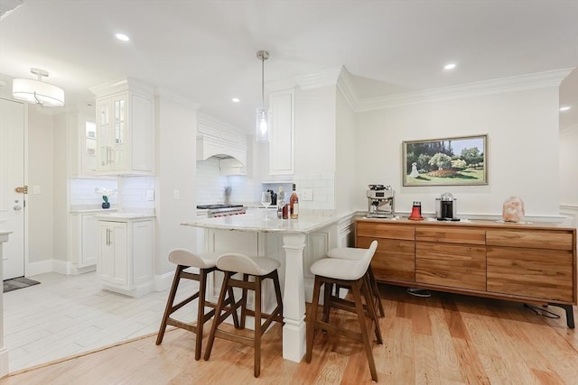 kitchen featuring light stone countertops, kitchen peninsula, white cabinetry, and hanging light fixtures