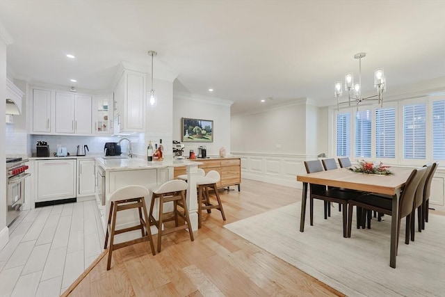 kitchen featuring light stone countertops, stove, decorative light fixtures, an inviting chandelier, and white cabinets