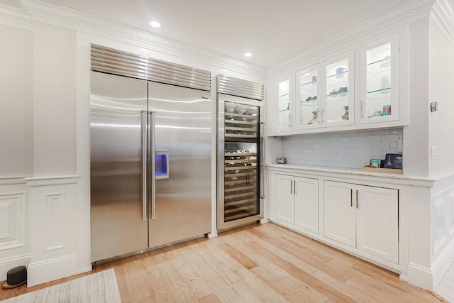 kitchen featuring white cabinets, wine cooler, built in refrigerator, light wood-type flooring, and tasteful backsplash