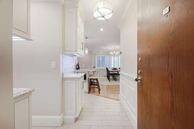 interior space featuring crown molding, light wood-type flooring, and an inviting chandelier