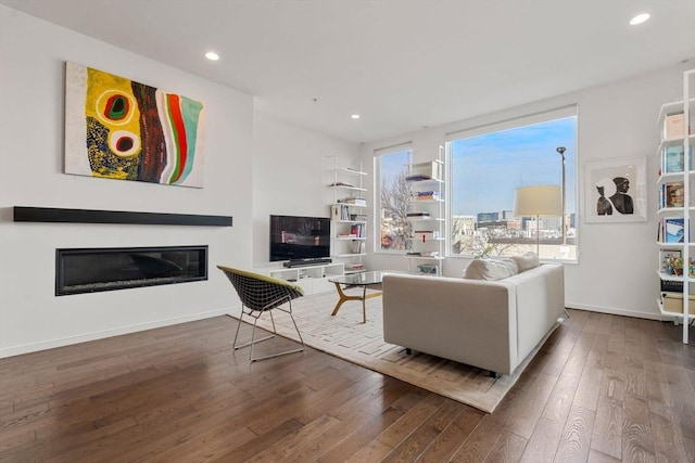 living room with hardwood / wood-style flooring, recessed lighting, baseboards, and a glass covered fireplace