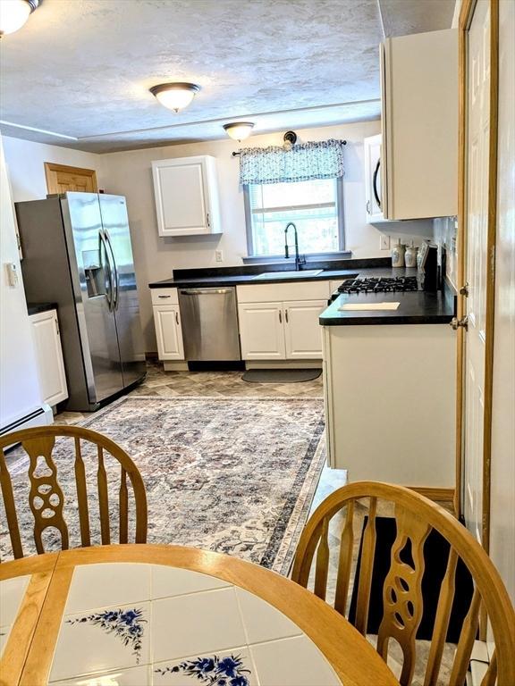 8 Intervale Rd, Rutland, MA 01543 - kitchen with stainless steel appliances, a sink, dark countertops, and white cabinetry