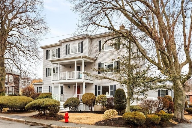 view of front of home featuring a balcony and a chimney