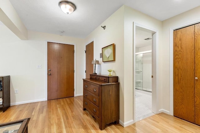 corridor featuring light wood-type flooring and baseboards