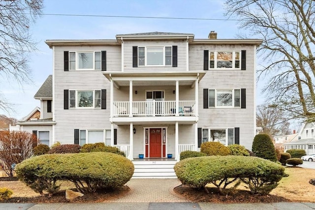 view of front of property featuring a chimney and a balcony