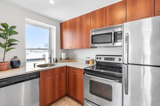 kitchen with brown cabinets, stainless steel appliances, a sink, and light countertops
