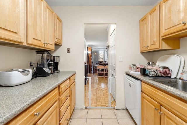 kitchen with dishwasher, sink, light tile patterned floors, and light brown cabinetry