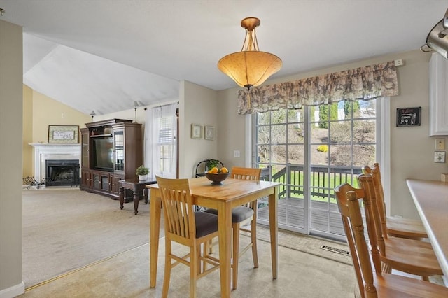 dining space featuring a fireplace and light carpet