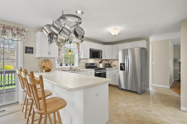 kitchen with light countertops, a peninsula, a wealth of natural light, and stainless steel appliances