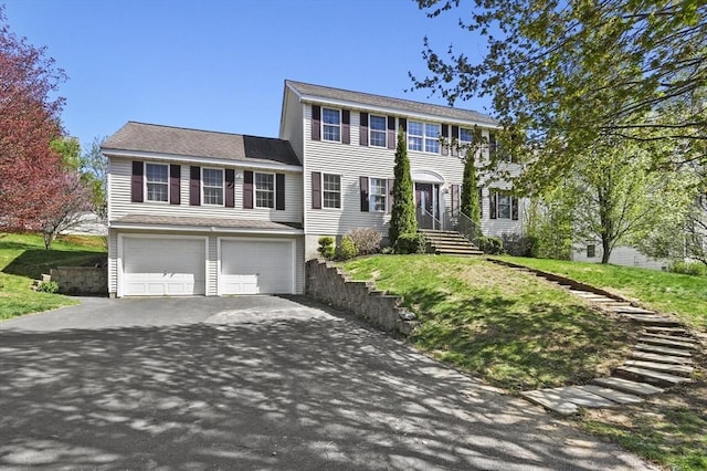 colonial-style house featuring an attached garage, driveway, and a front lawn