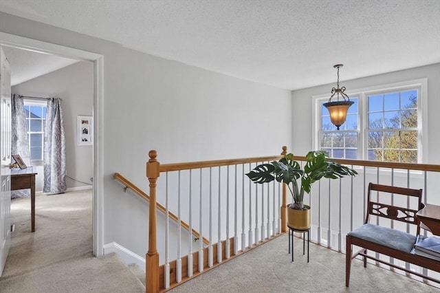 interior space with baseboards, carpet flooring, a textured ceiling, and an upstairs landing