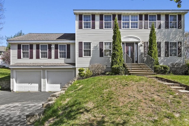 colonial home with a garage, aphalt driveway, and a front yard