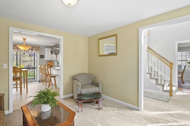 living area featuring stairs, baseboards, and carpet