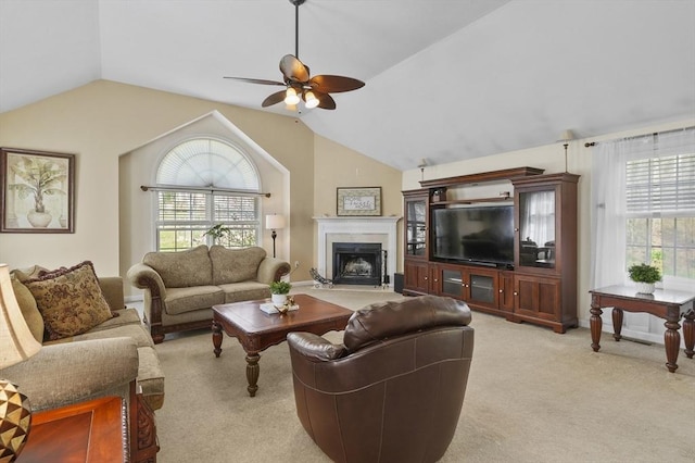 living area featuring ceiling fan, vaulted ceiling, light carpet, and a fireplace with flush hearth