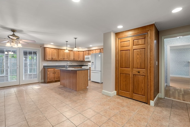 kitchen with light hardwood / wood-style flooring, white appliances, a center island with sink, decorative light fixtures, and ceiling fan