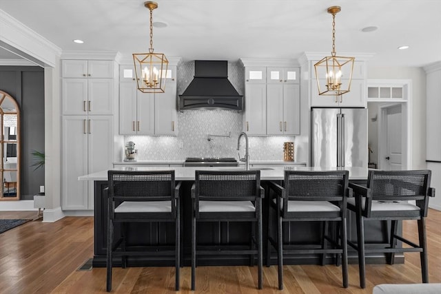 kitchen featuring custom exhaust hood, high end refrigerator, light countertops, and a notable chandelier