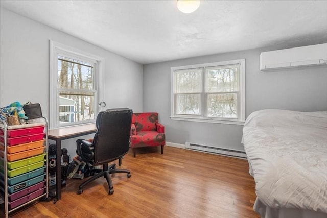 office space featuring hardwood / wood-style floors, a wall unit AC, a wealth of natural light, and baseboard heating