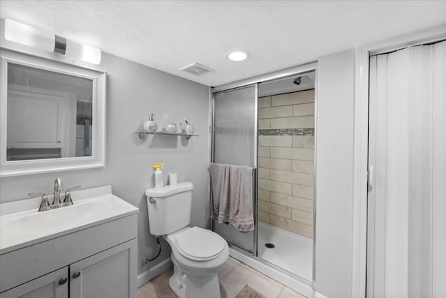 bathroom with tile patterned flooring, vanity, toilet, and a shower with shower door