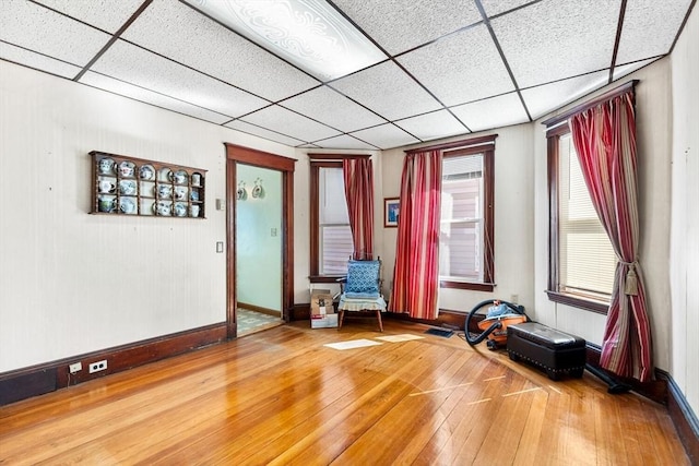 interior space featuring baseboards, a paneled ceiling, and hardwood / wood-style flooring