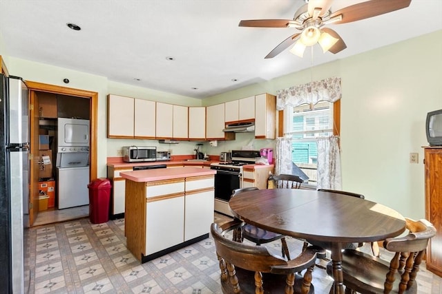 kitchen featuring a kitchen island, appliances with stainless steel finishes, stacked washing maching and dryer, light countertops, and under cabinet range hood