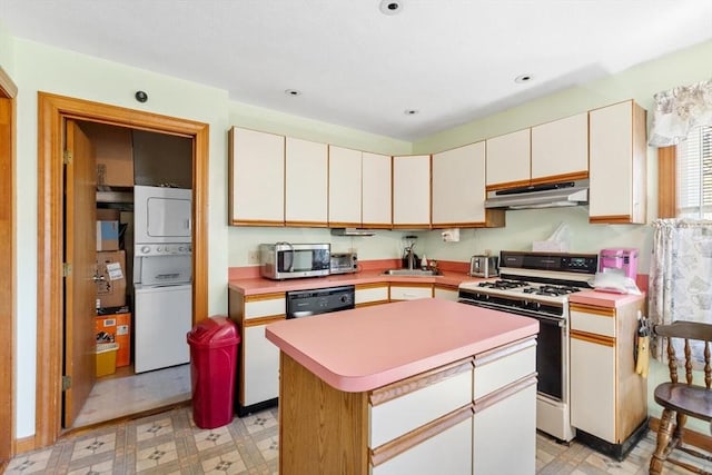 kitchen featuring stacked washing maching and dryer, white gas stove, light countertops, stainless steel microwave, and under cabinet range hood