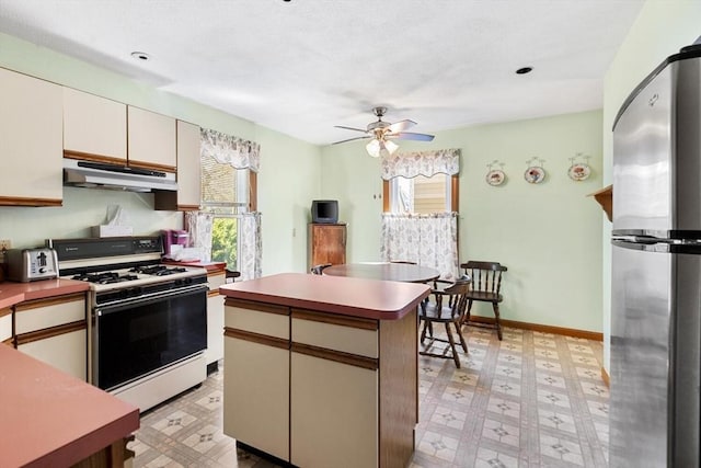kitchen with freestanding refrigerator, light floors, white range with gas cooktop, under cabinet range hood, and a ceiling fan