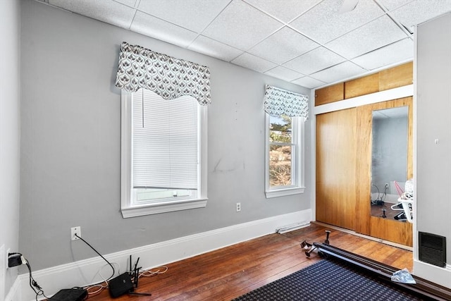 workout area with baseboards, a paneled ceiling, hardwood / wood-style floors, and visible vents