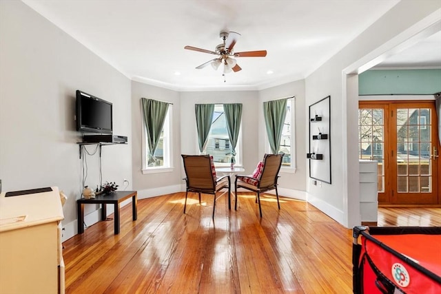 sitting room featuring a ceiling fan, baseboards, ornamental molding, and light wood finished floors