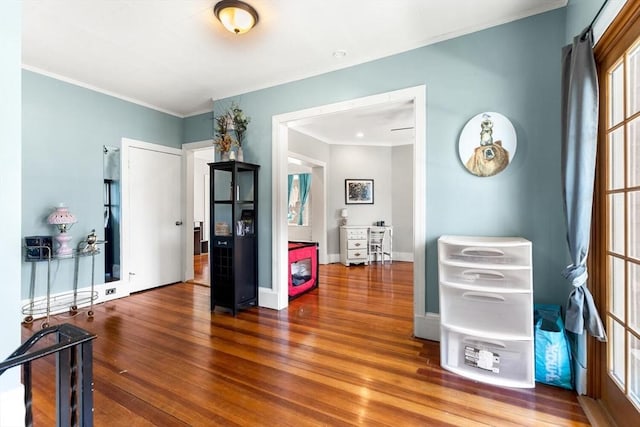 interior space featuring crown molding, baseboards, and wood finished floors