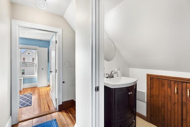 bathroom featuring vanity, baseboards, vaulted ceiling, and hardwood / wood-style flooring