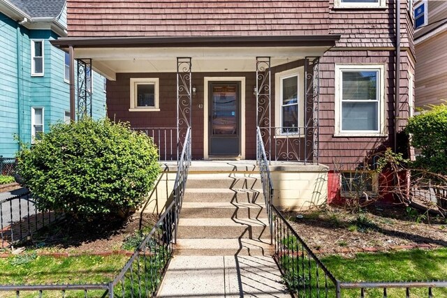 entrance to property featuring covered porch and fence