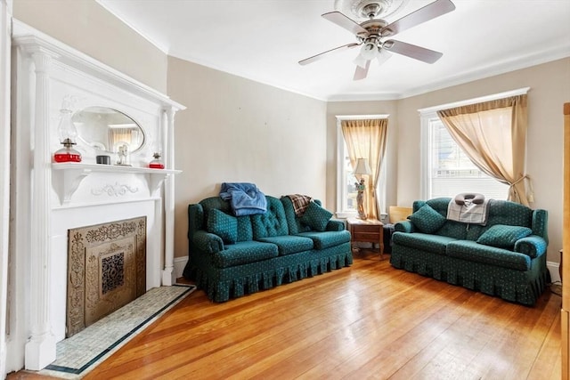 living room with ornamental molding, ceiling fan, a premium fireplace, and hardwood / wood-style floors