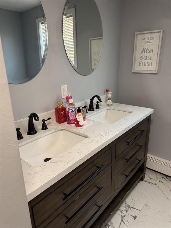 bathroom with double vanity, marble finish floor, and a sink