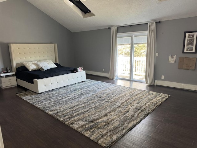 bedroom featuring vaulted ceiling with skylight, dark wood-style flooring, access to exterior, a textured ceiling, and baseboard heating