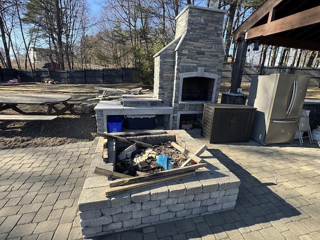 view of patio / terrace with an outdoor stone fireplace and fence