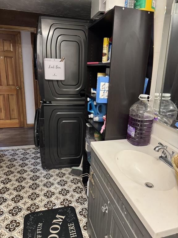 interior space featuring tile patterned floors, stacked washer / dryer, laundry area, and a sink