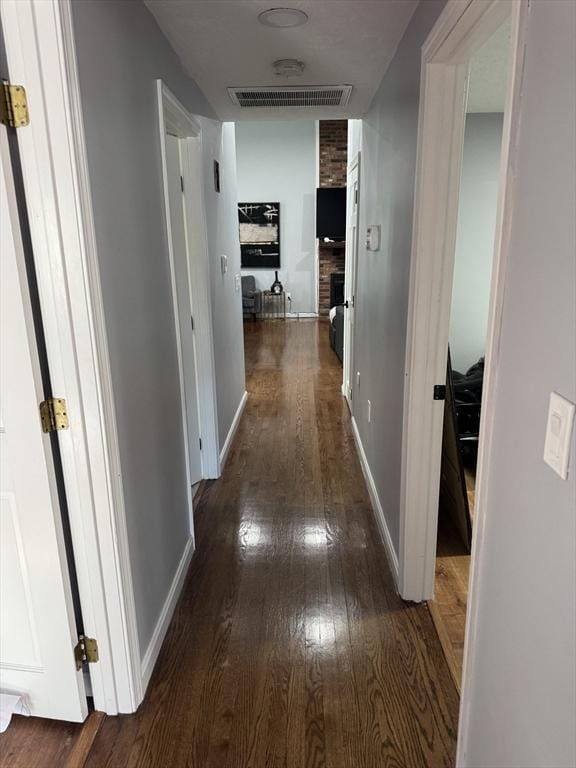 hall with hardwood / wood-style flooring, baseboards, and visible vents