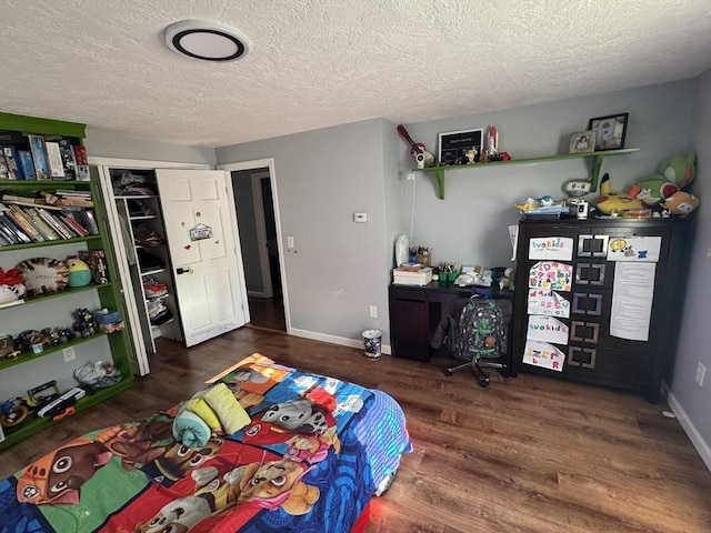 bedroom featuring a textured ceiling, baseboards, and wood finished floors