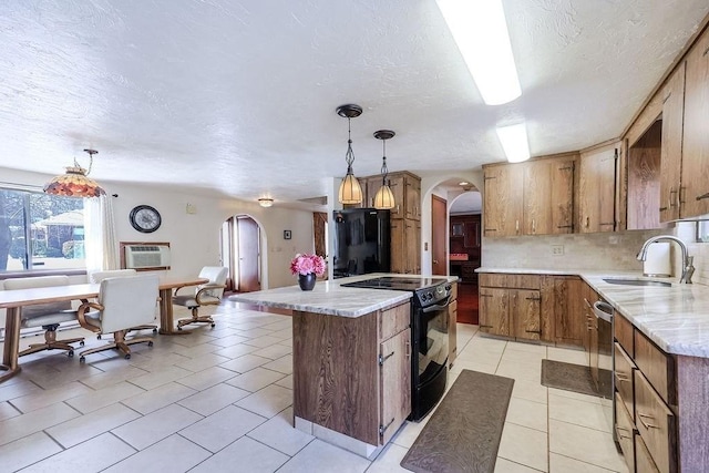 kitchen with arched walkways, a kitchen island, a sink, decorative backsplash, and black appliances