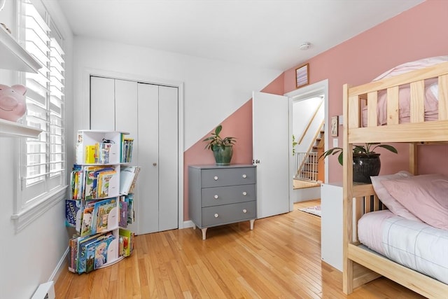 bedroom with a closet, baseboard heating, and hardwood / wood-style flooring